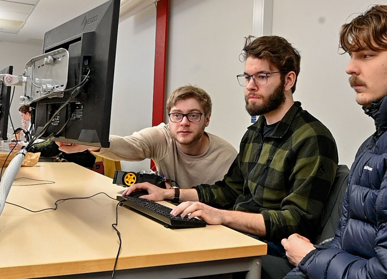 Tre studenter tittar på en datorskärm.