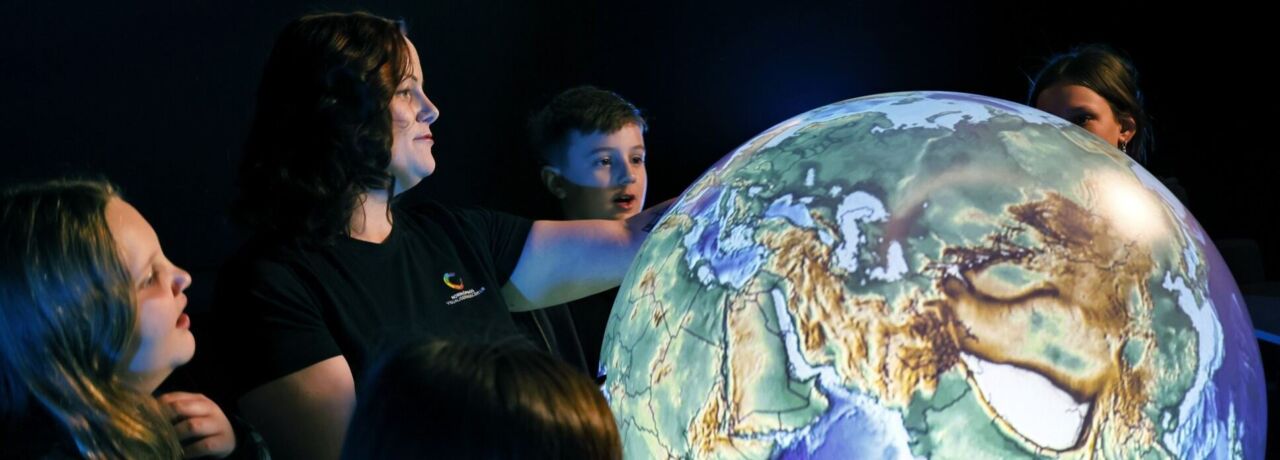 Människor står runt en upplyst jordglob