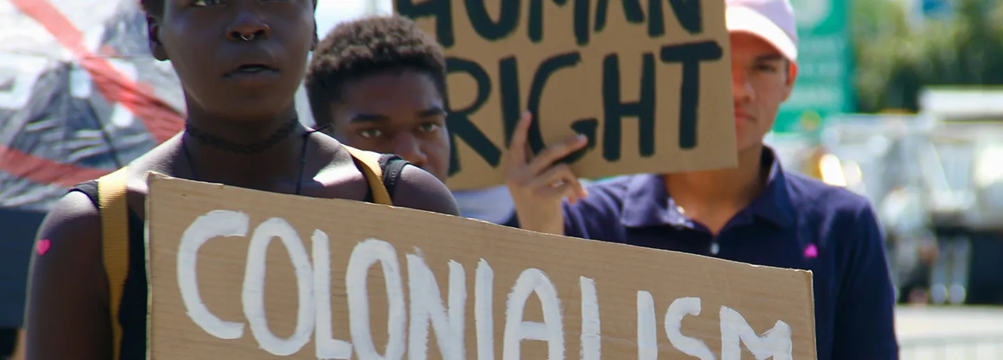 Plakat med texten COLONIALISM IS INDIGENOUS GENOCIDE