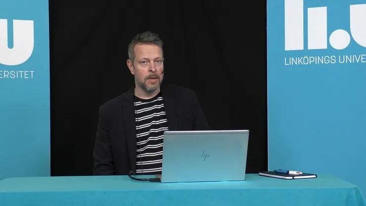 Föreläsaren står framför sin dator.