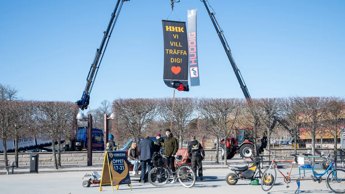 En utomhusmässa vid Linköpings universitet där industriföretag och studenter möts. Två stora kranar håller upp banderoller, och flera personer står runt specialbyggda cyklar och diskuterar.