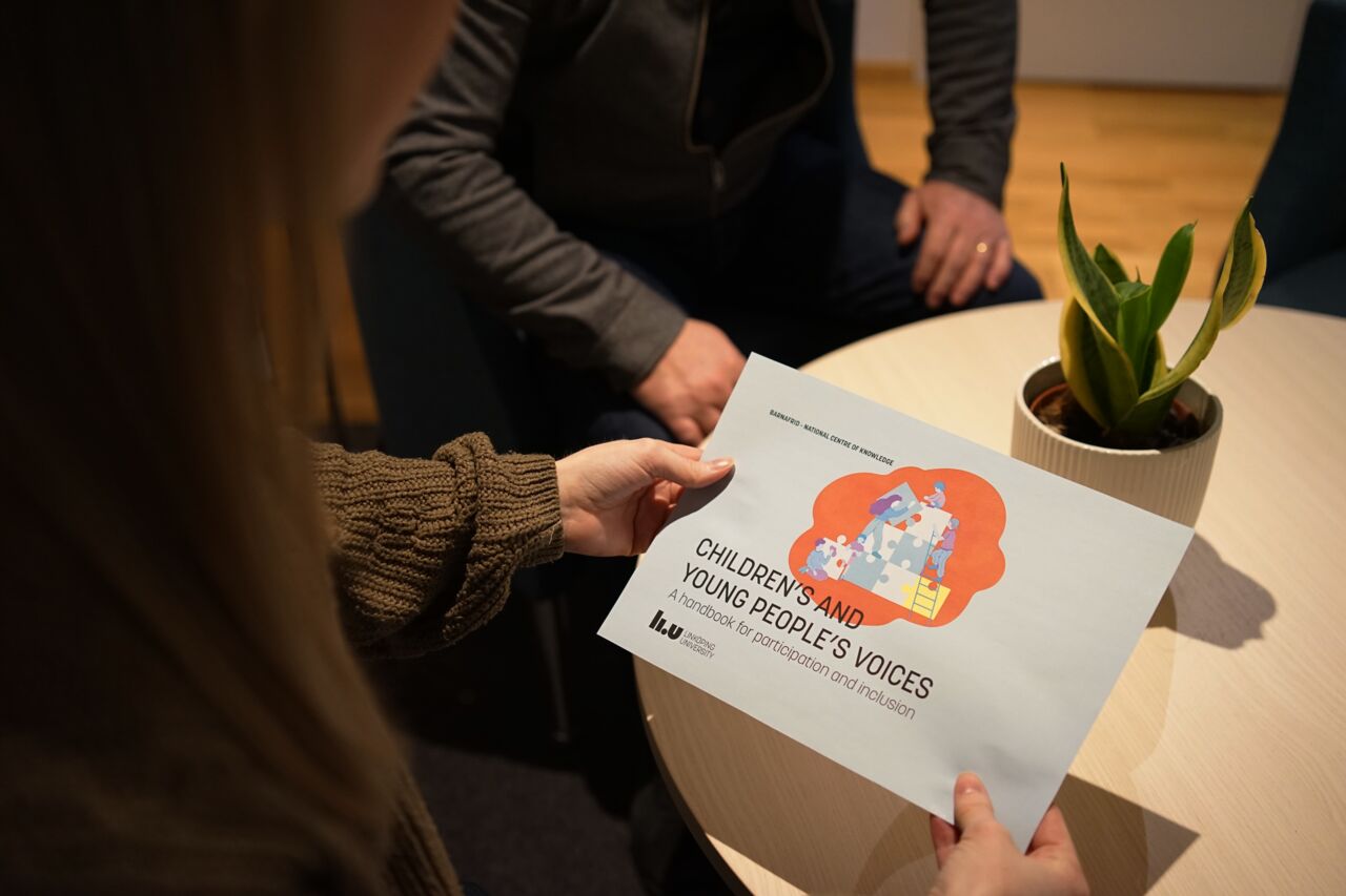 Over the shoulder perspective of a girl holding a handbook.