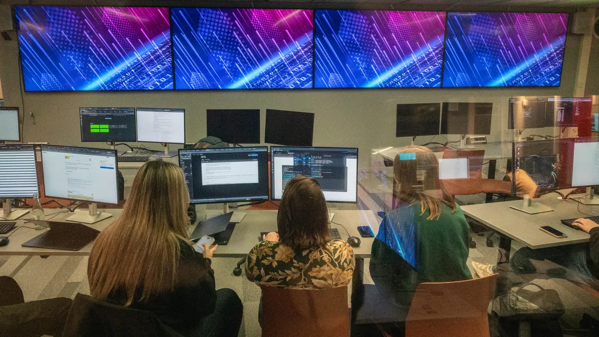 Tre studenter framför datorskärmar i cybersäkerhetslabbet