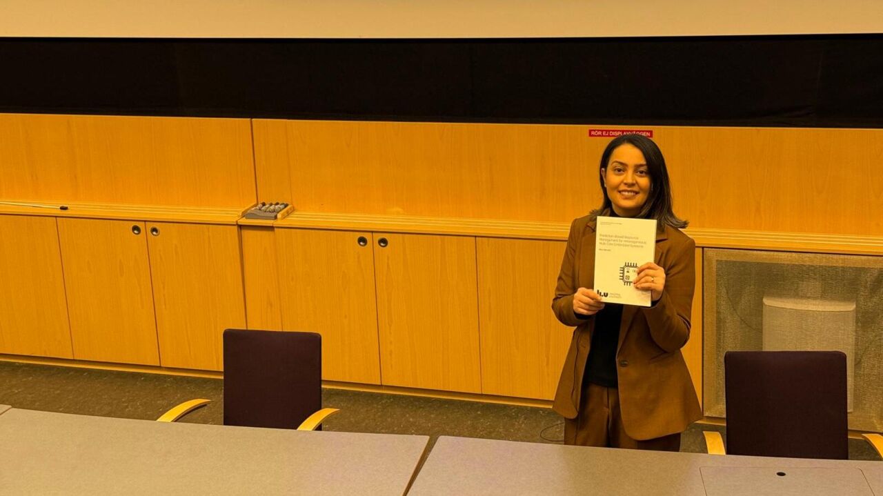 Mina Niknafs shows her printed thesis in the lecture hall.
