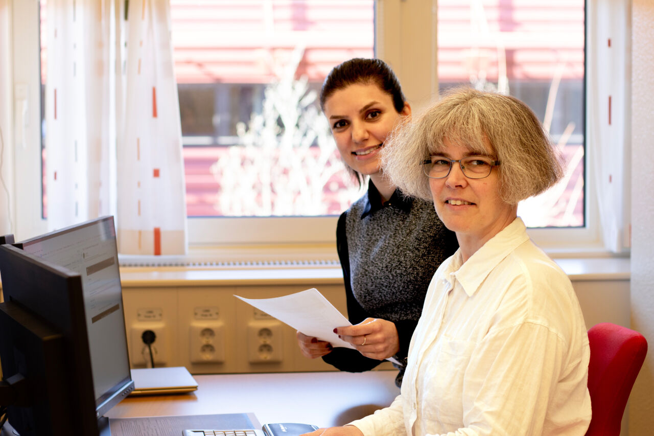 Två kvinnor vid skrivbord framför datorskärmar