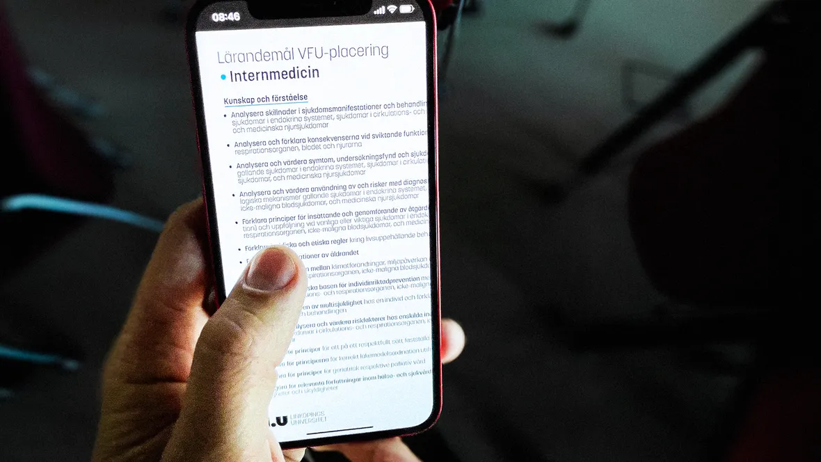 Hand håller i telefon som visar dokument.