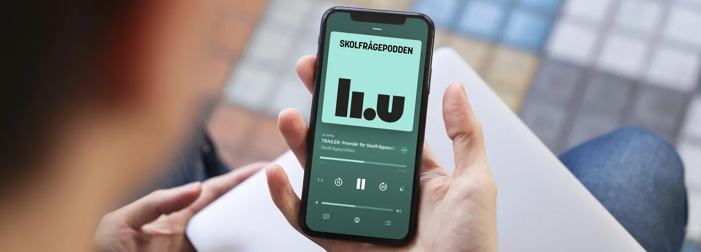 Person håller upp mobiltelefon som visar Skolfrågepodden på skärmen.
