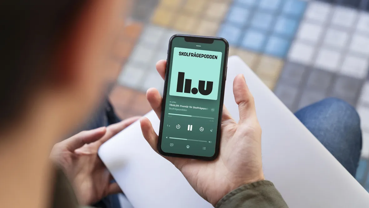 Person håller upp mobiltelefon som visar Skolfrågepodden på skärmen.