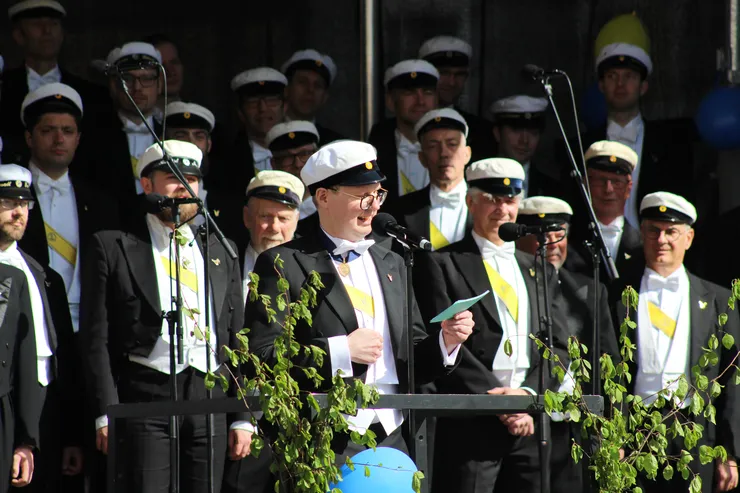 En man håller tal framför en kör