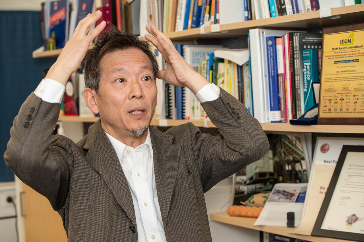 Manlig forskare gestikulerar i diskussion i kontorsmiljö.