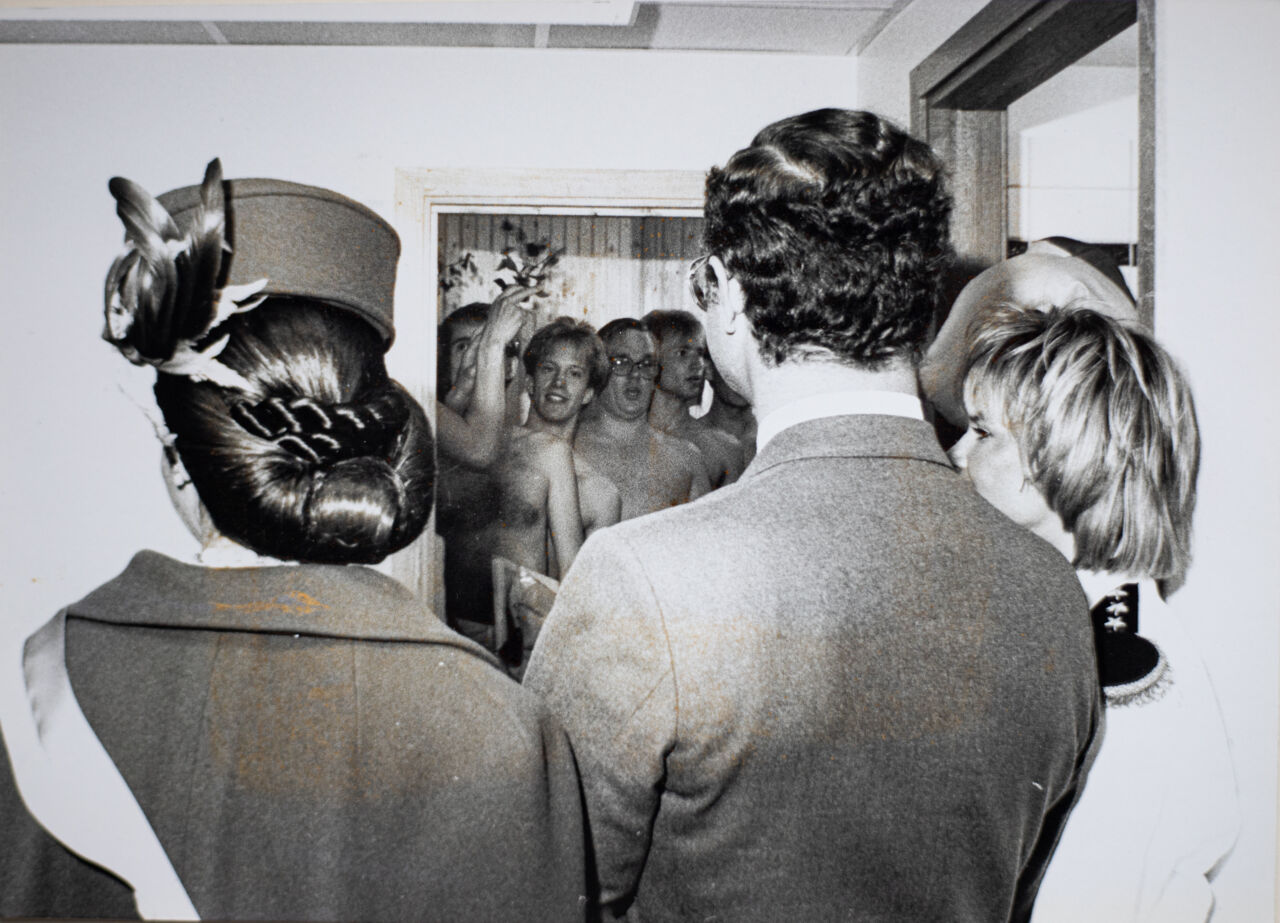 Drottningen, kungen och Helen Köpman framför en bastu, bilden är tagen bakifrån.