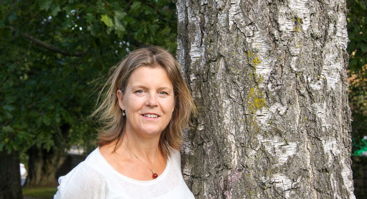 Kvinna som står bredvid ett träd.