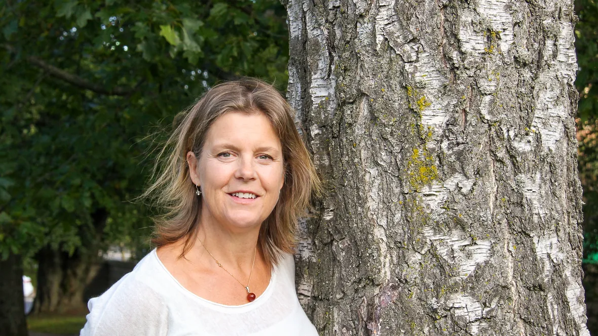 A woman standing by a tree.