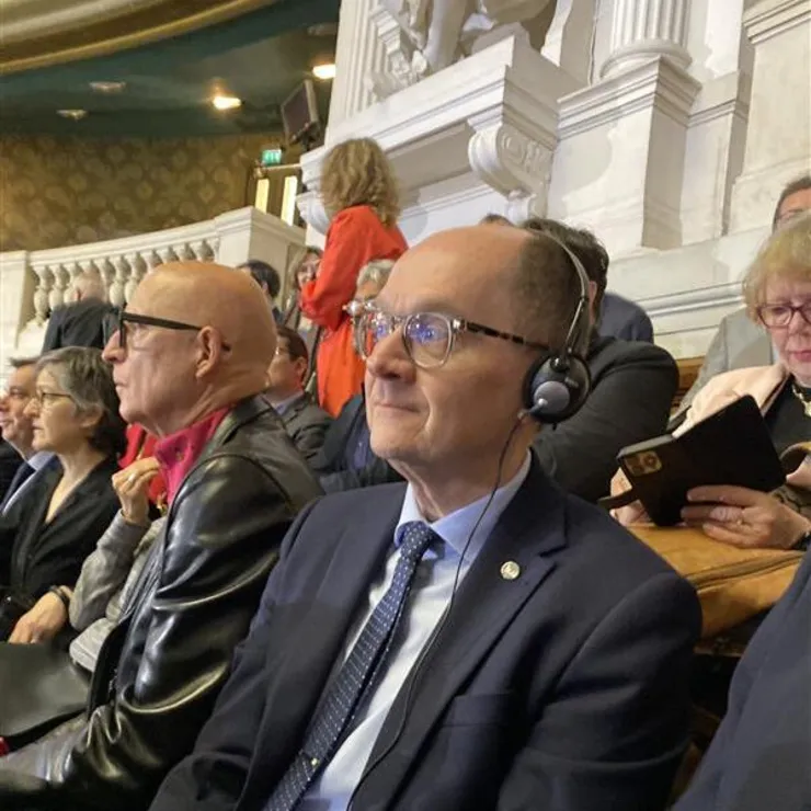 LiU:s rektor lyssnar på en konferens genom hörlurar i sällskap med andra.