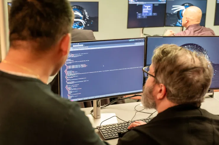 A person sits in front of a computer screen showing code.