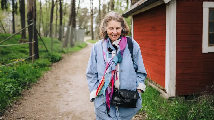 Äldre kvinna som går ute i skogen.