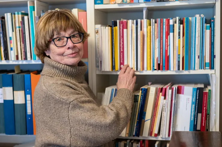 Kvinnlig professor emerita framför en bokhylla