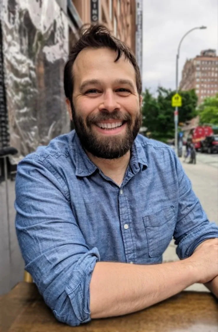 Dustin Stoltz, sitting at a table in urban setting