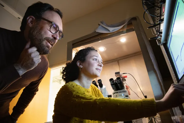 Two researchers in a lab discuss a graph on a computer screen.