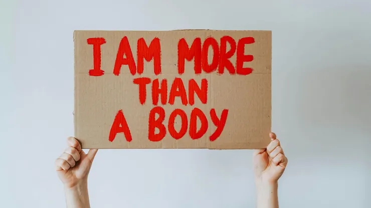 hands holding up a sign with red text