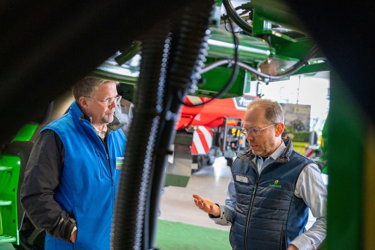 Två män samtalar vid stora jorsbruksmaskiner.