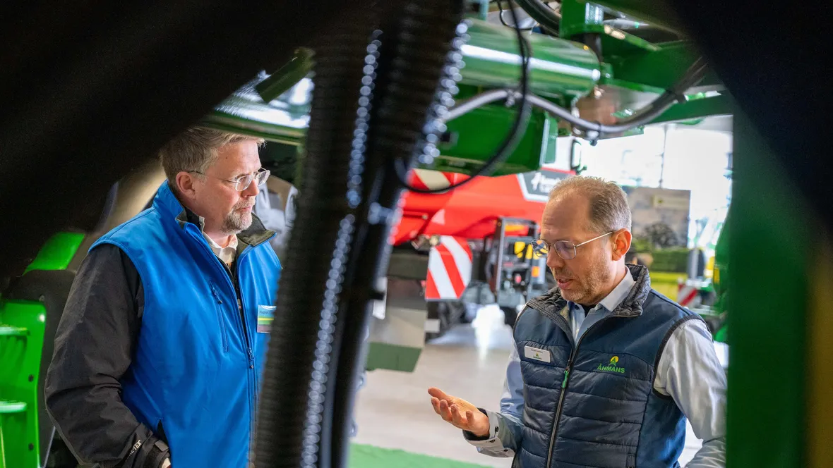Två män samtalar vid stora jorsbruksmaskiner.