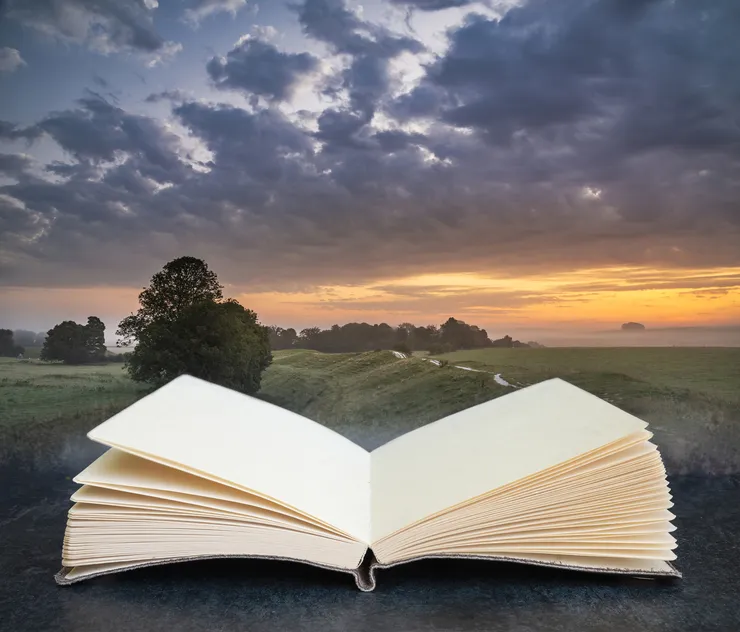 Sunset over a beautiful landscape, in the foreground is an open book.