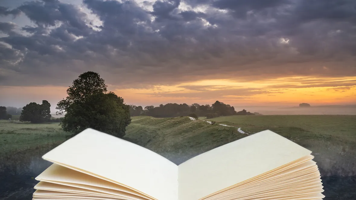 Sunset over a beautiful landscape, in the foreground is an open book.