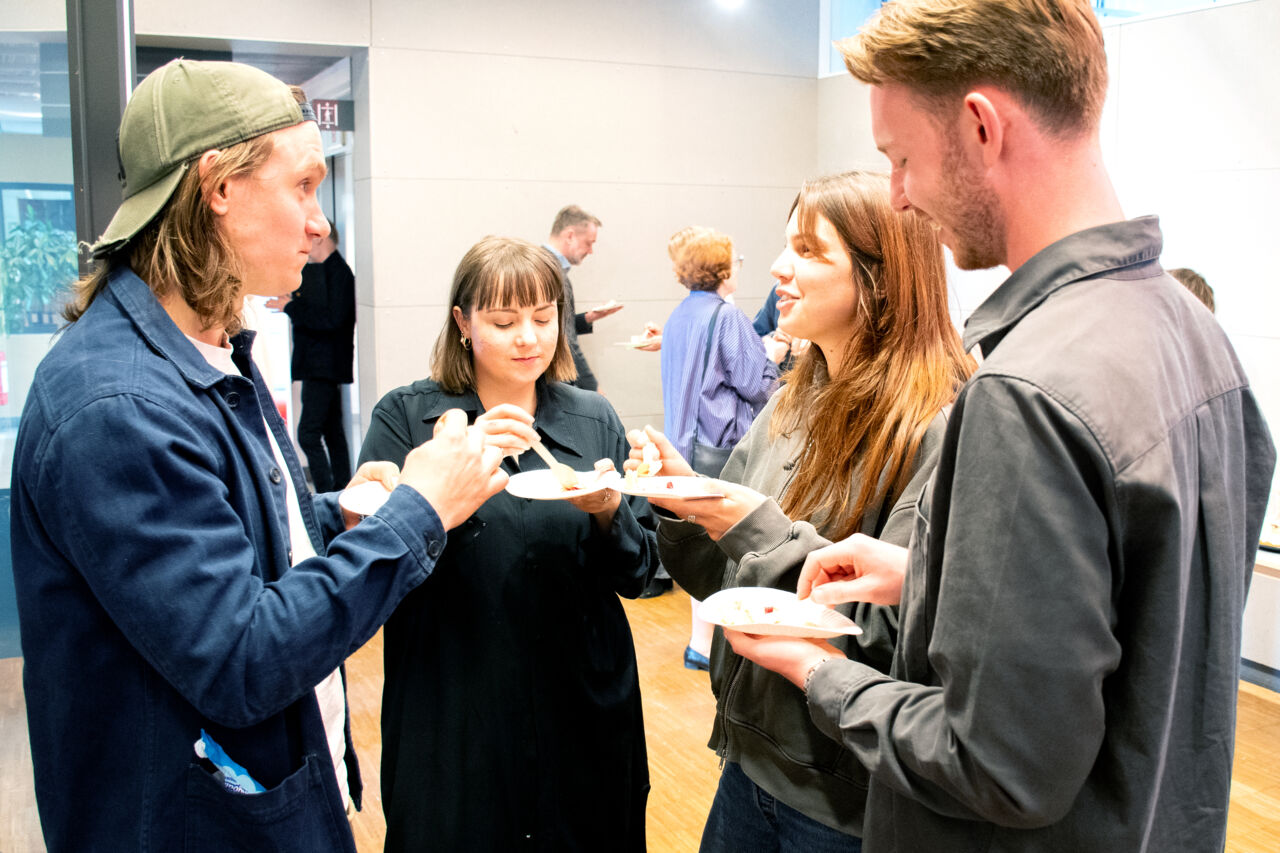 Fyra personer står ihop och fikar. 