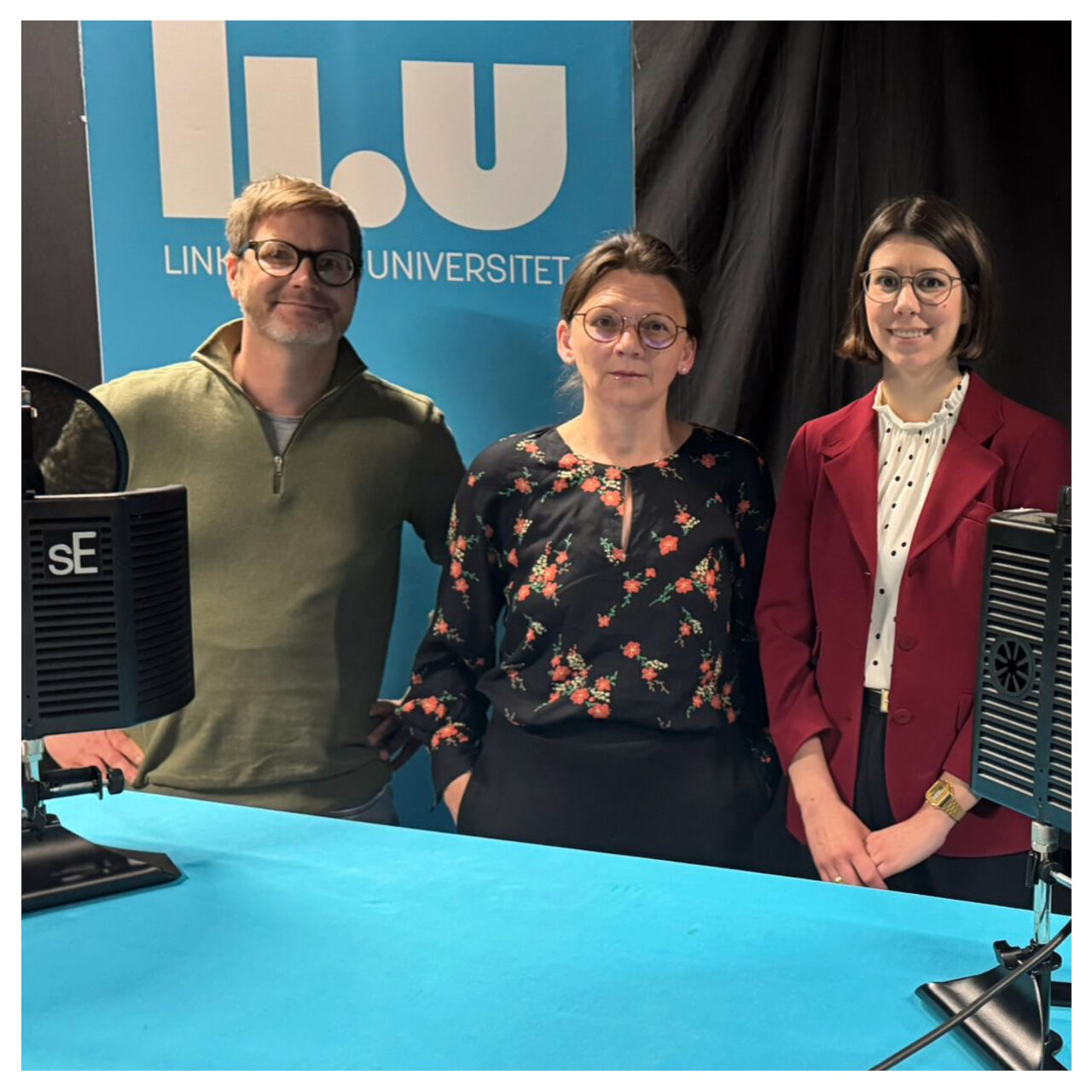 Tre personer står i en inspelningsstudio och tittar mot kameran.