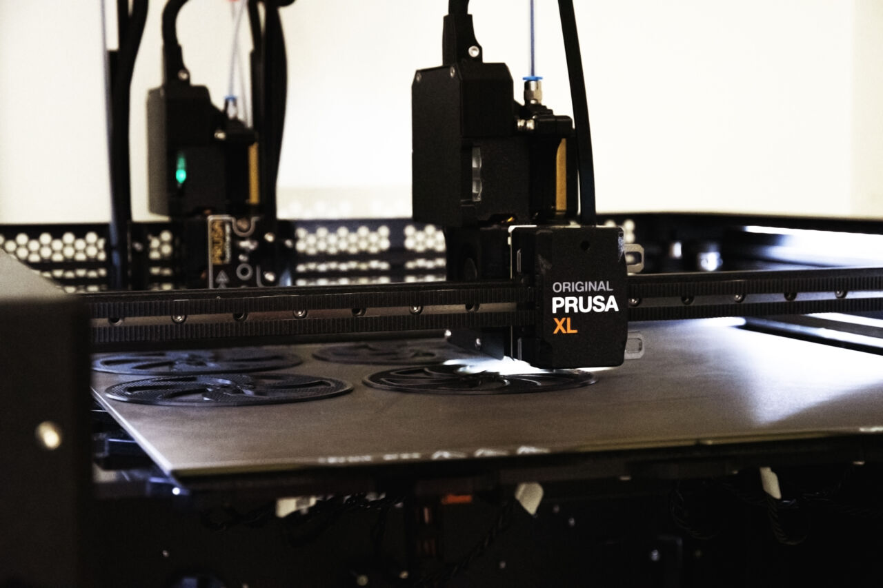 Närbild på en svart 3D-printer som producerar reservdelar.