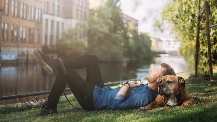 en kille och hans hund ligger och vilar på en gräsmatta