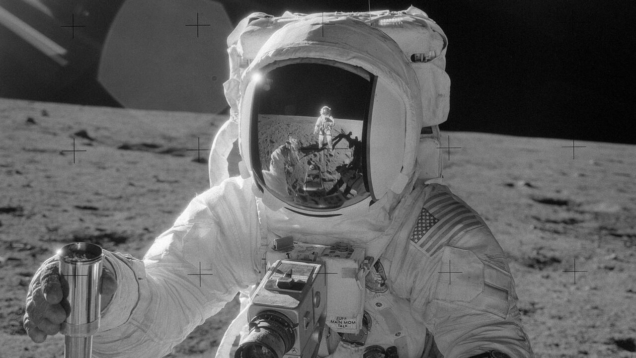Black and white picture of a man on the moon wearing a space suit