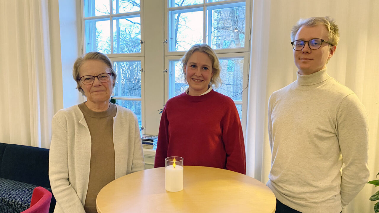 Två kvinnor och en man står vid ett runt bord