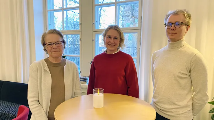 Två kvinnor och en man står vid ett runt bord