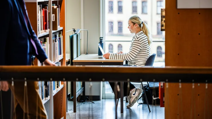 Kvinnlig student pluggar i ett bibliotek