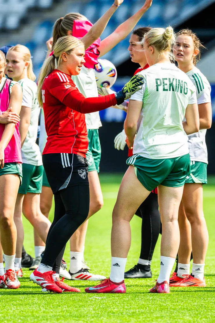 Kvinnlig fotbollsspelare ger en annan spelare en klapp på axeln