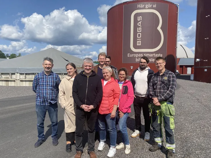 A group of people standing in front of a biogas plant