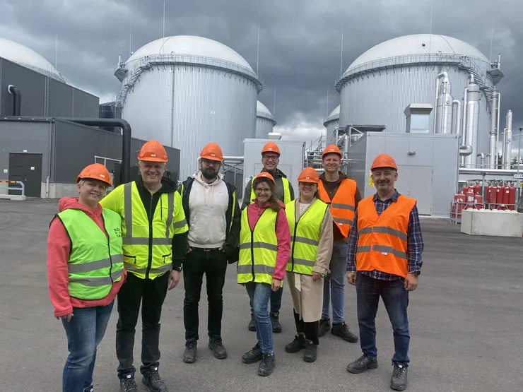 A group of people standing in front of a biogas plant