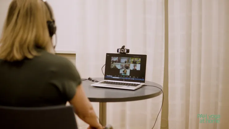 En kvinna som sitter vid en laptop med ryggen mot kameran.