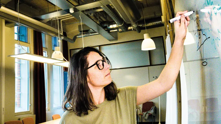 Woman taking notes on whiteboard.