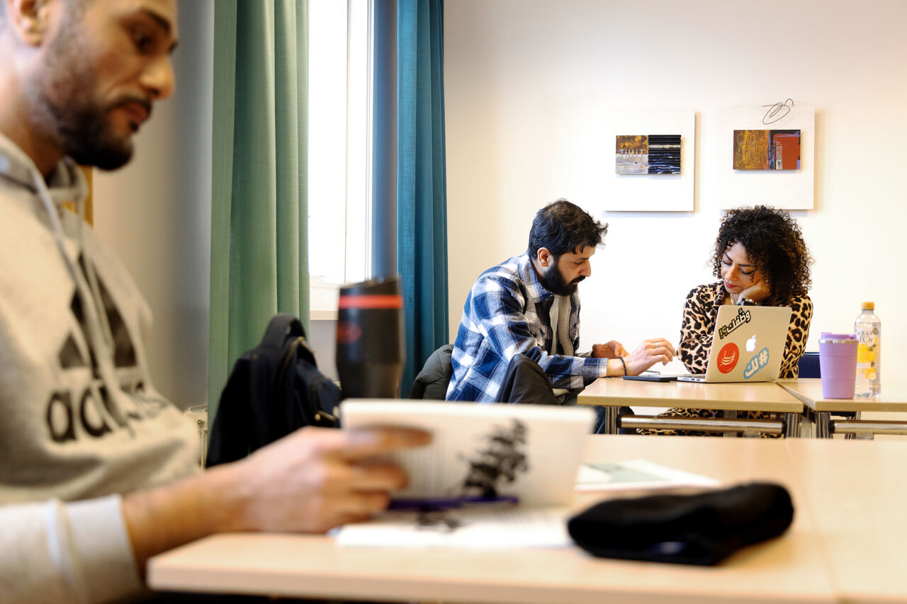 Samtal mellan kvinnlig lärare och yngre vuxenstudent i ett klassrum.