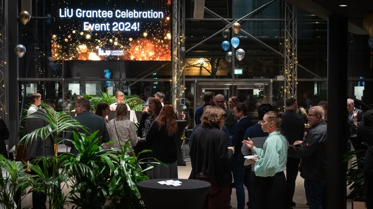Människor på ett firarevent bland bord och ballonger