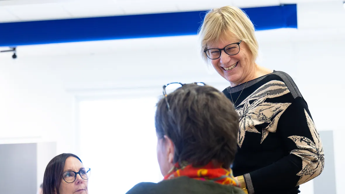 Leende kvinnlig lärare undervisar äldre studenter.