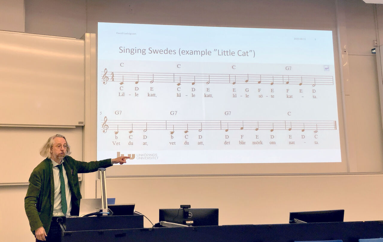 Man föreläser och pekar på bild med noter