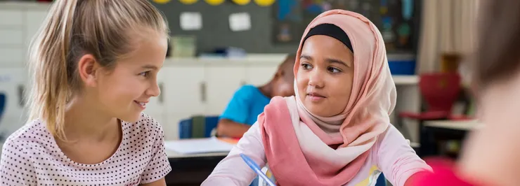 Two young girls in a classroom.