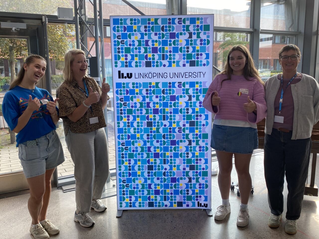 Fyra glada kvinnor vid en reklamskylt för LiU