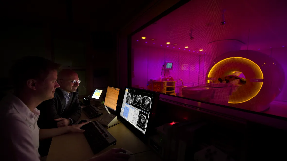 Two scientists are sitting infront of an MRI