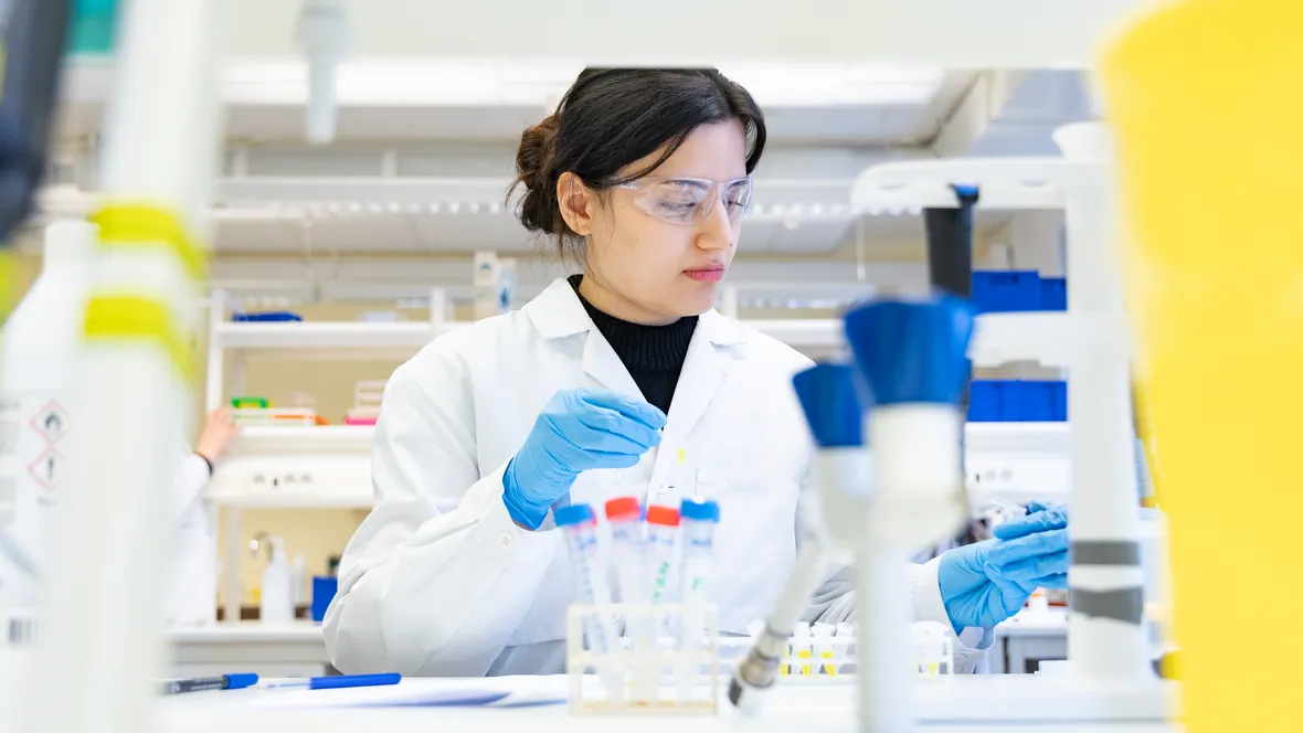 Ung kvinna analyserar prover i labbmiljö.