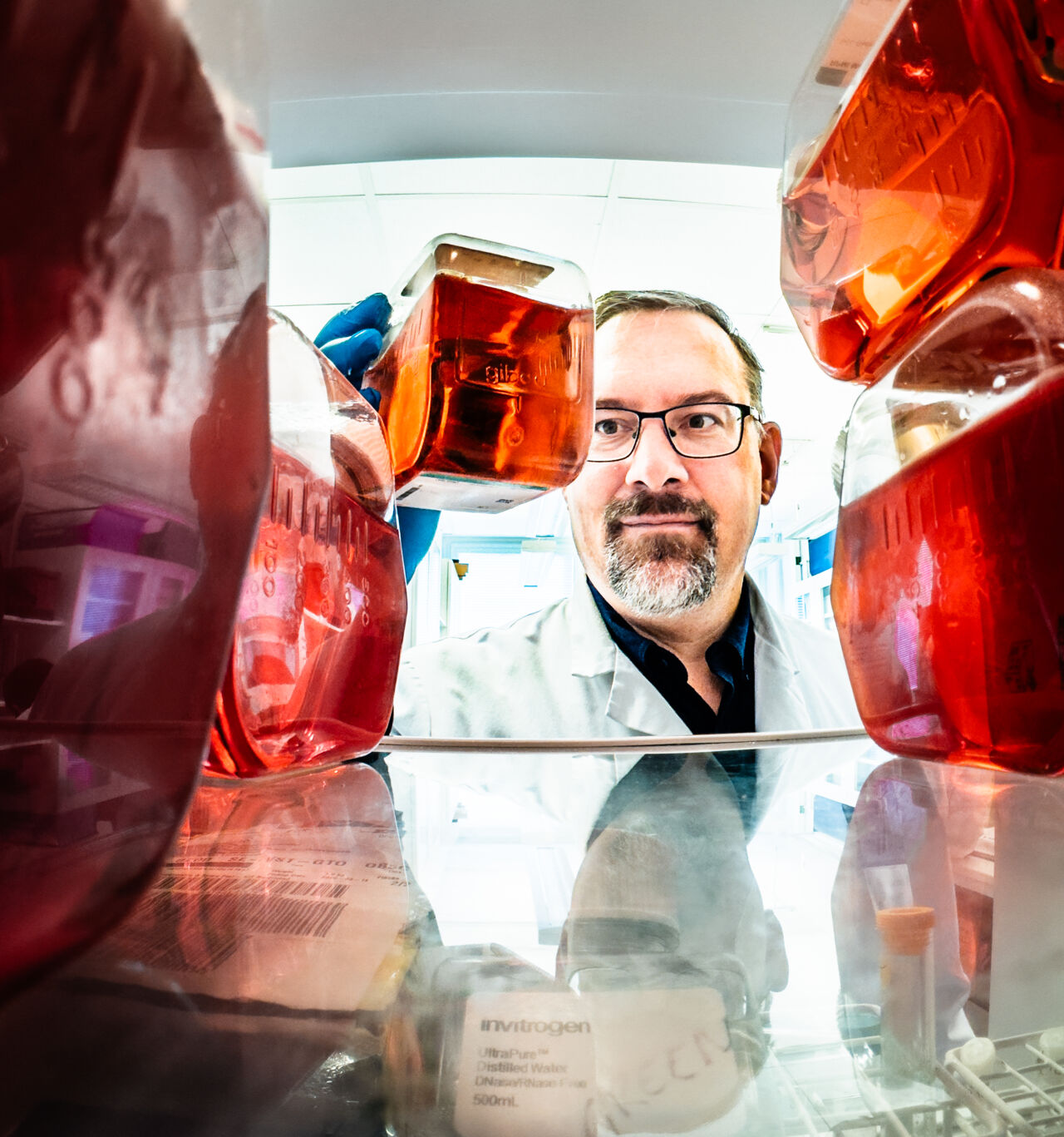Man taking bottles from a cabinet.